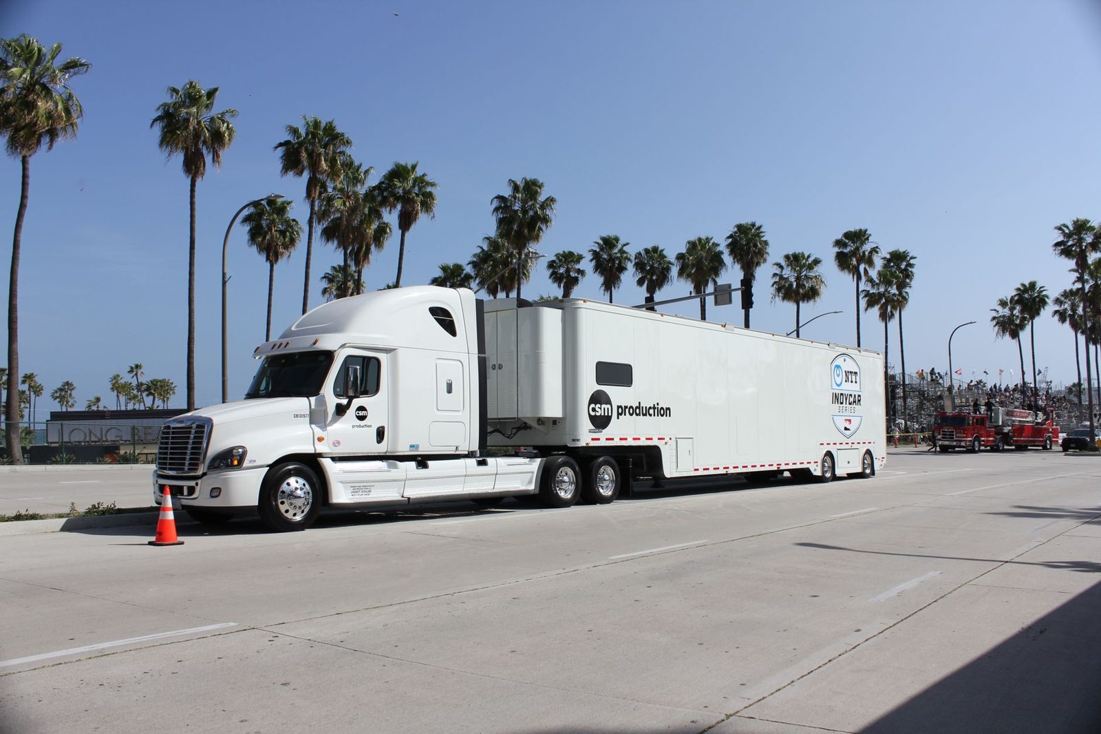 A production truck parked on a palm lined street