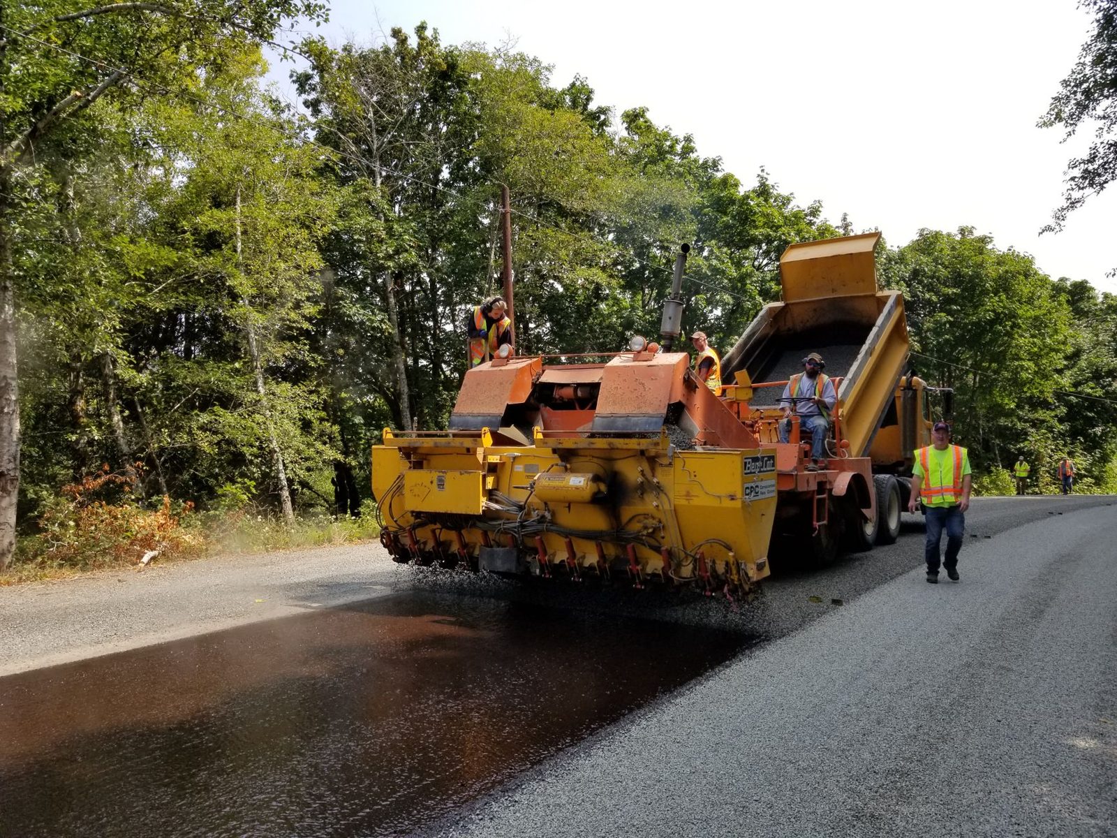 A paving machine working a tree lined road