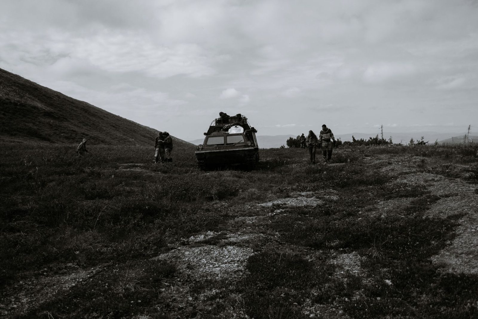 Military vehicles and troops on grassy coastal hills