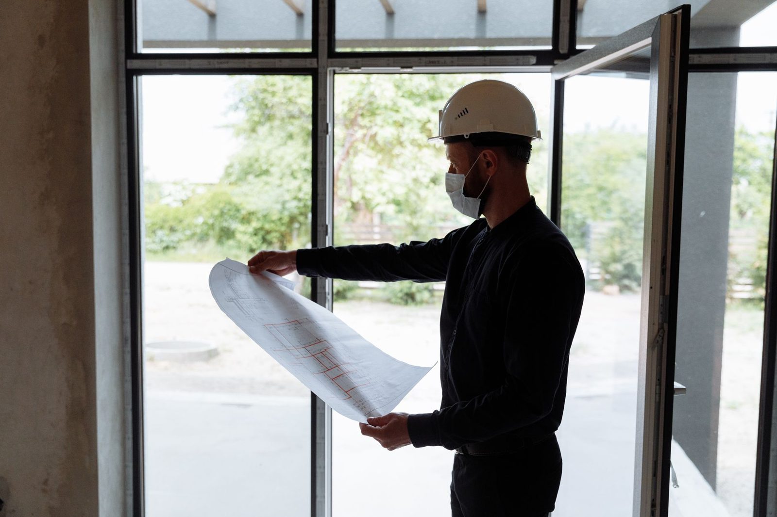 A superintendent in a hard hat reviewing plans at a window