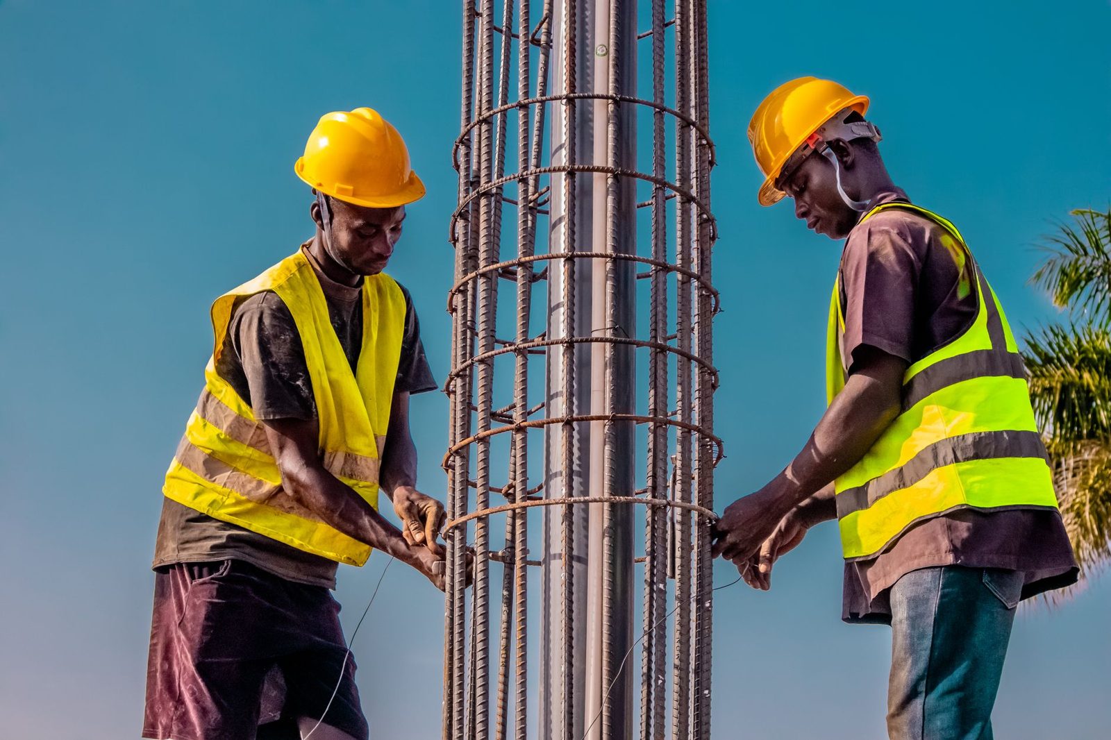 Two workers tying rebar for a concrete column