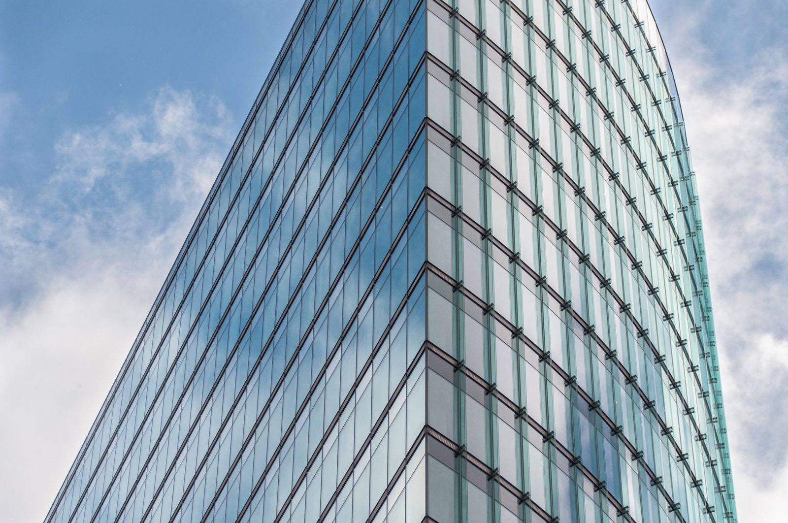 A glass office tower against a blue sky