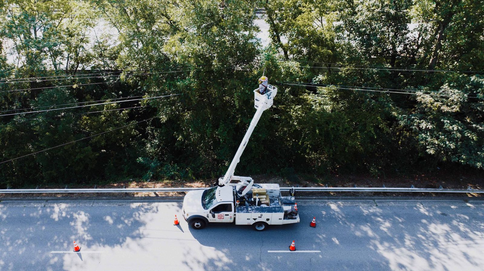 A utility bucket truck working power lines along a road
