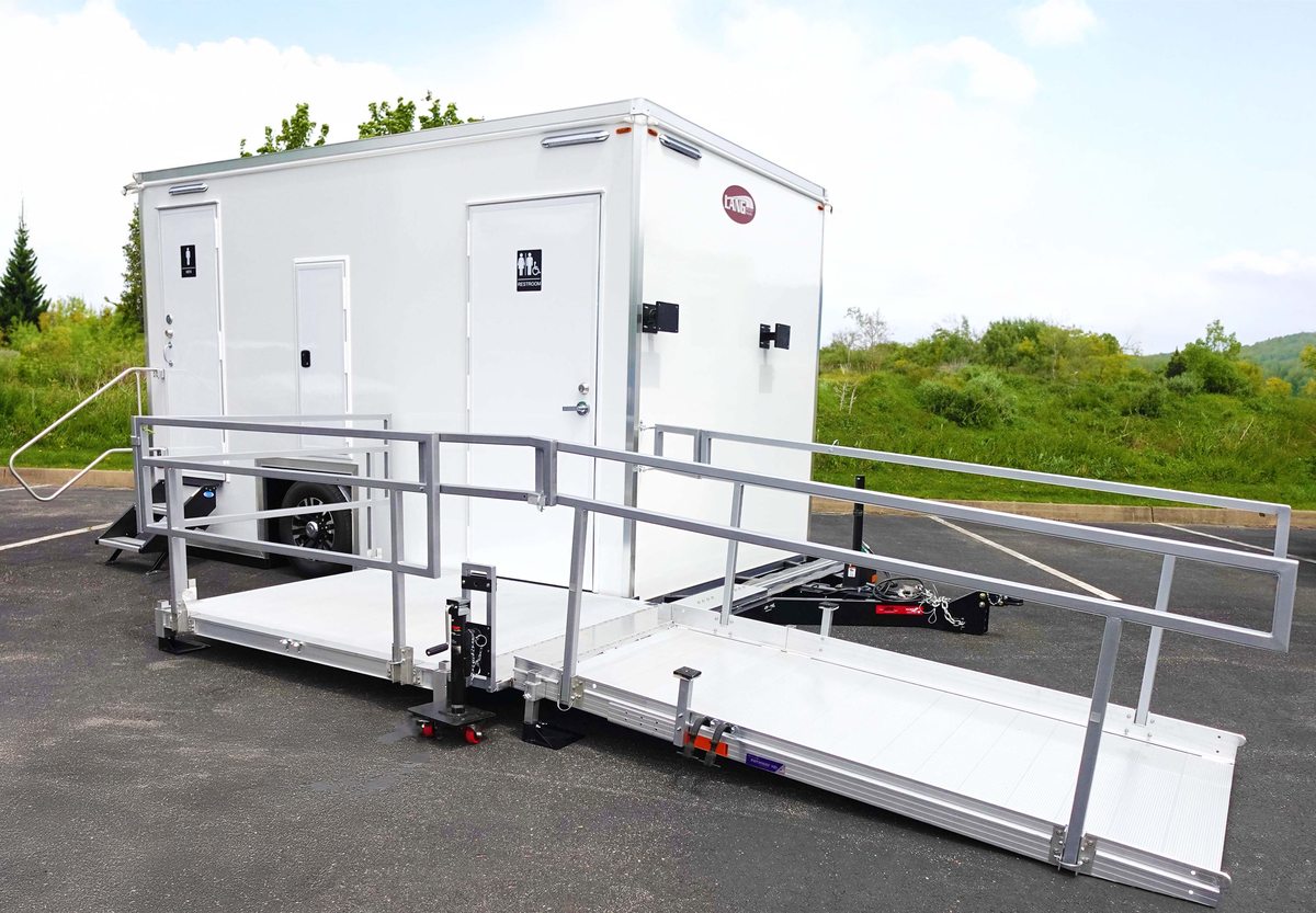 ADA restroom trailer with wheelchair ramp installed alongside two standard restroom stations