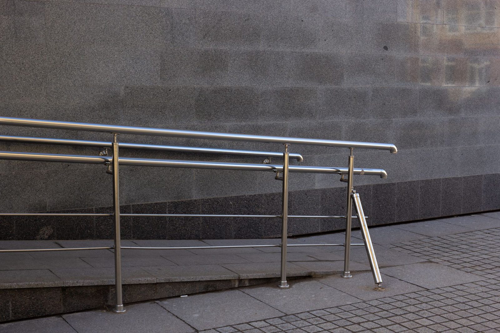A handrail ramp along a building wall
