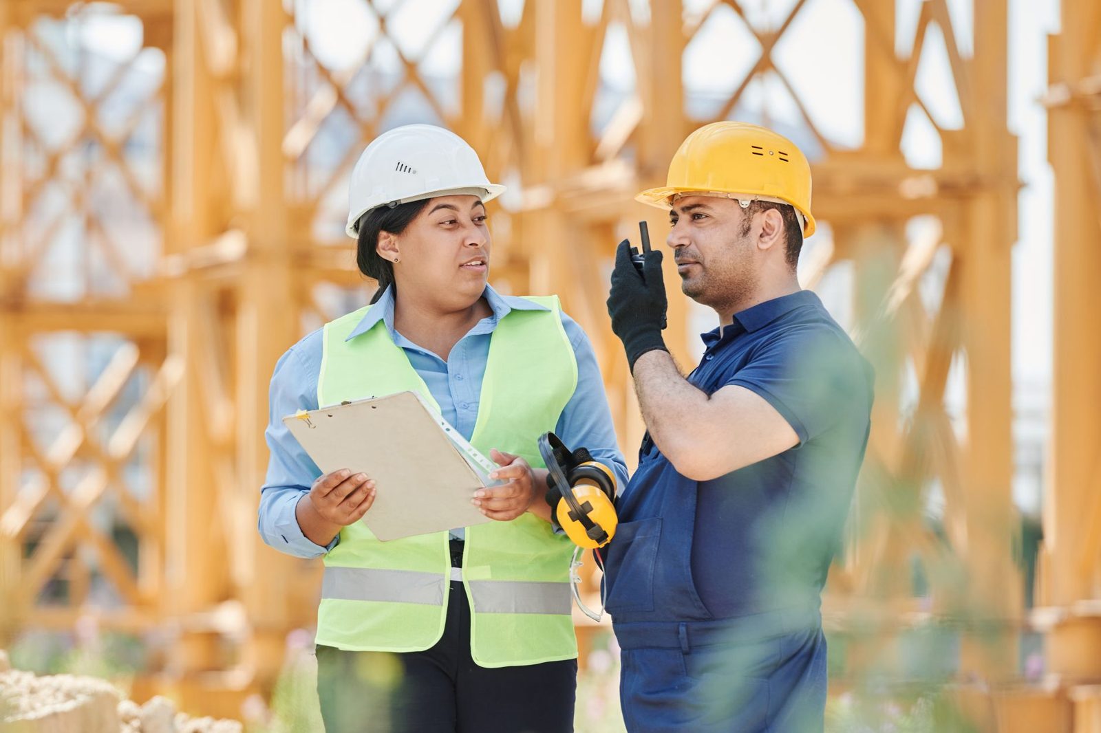 Two workers in hard hats reviewing notes on a site
