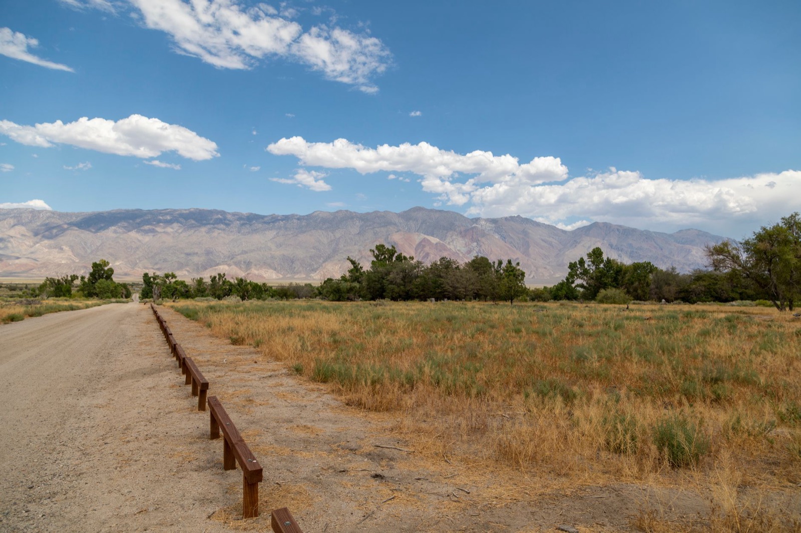 A dirt access road and a dry ditch running toward bare desert mountains