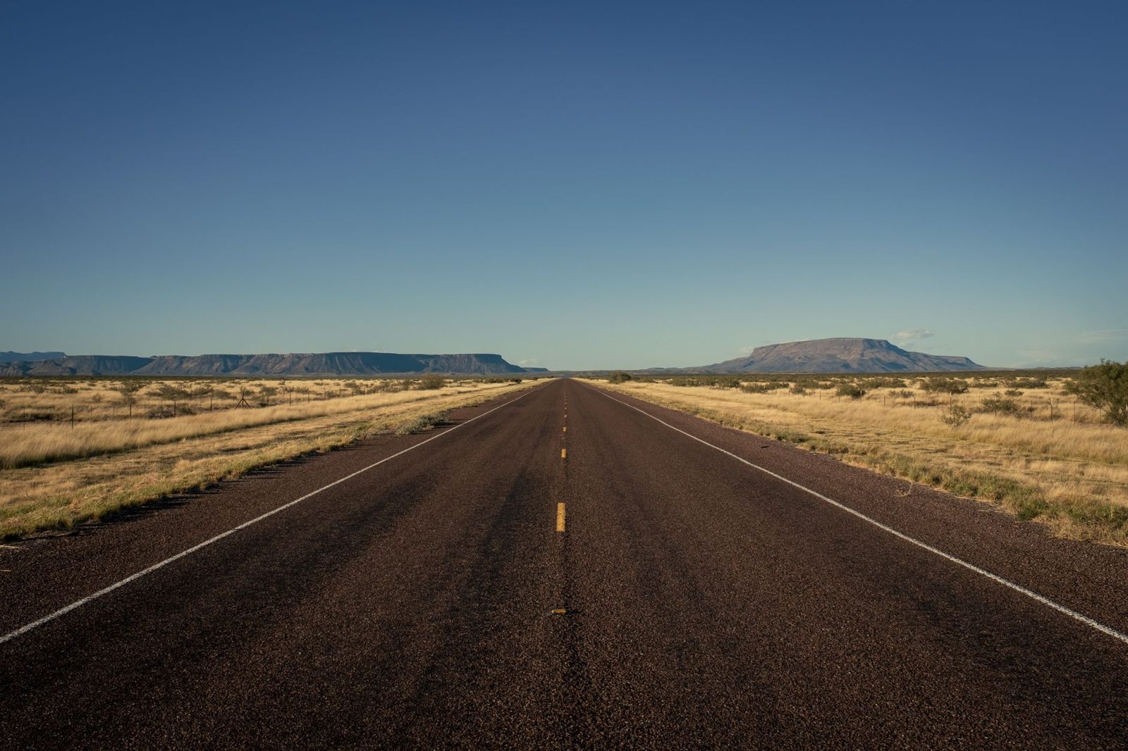 A long highway running toward a mesa in West Texas
