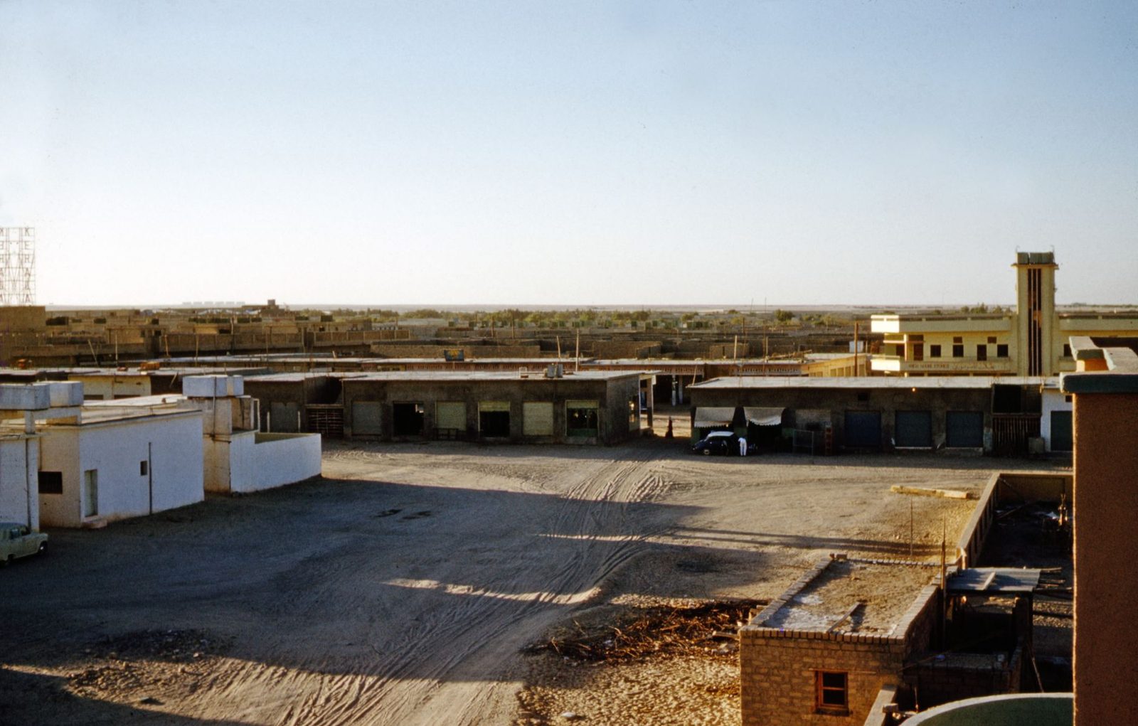 A paved lot beside low buildings and a tower on an installation