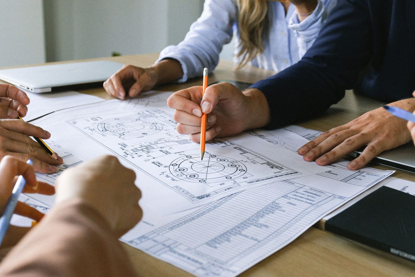 Hands marking up building plans on a table