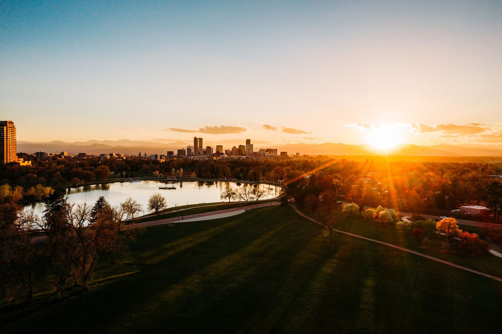 The Denver skyline at sunset seen across a city park lake