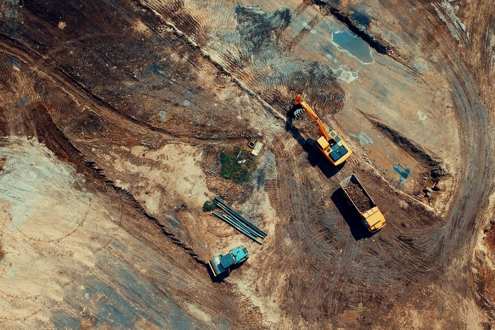 An aerial view of excavators and haul trucks spread across a large earthwork site